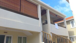 Un bâtiment à deux étages doté d’un balcon à l’étage supérieur, d’une balustrade en bois et d’une fenêtre sur laquelle est accrochée une serviette.