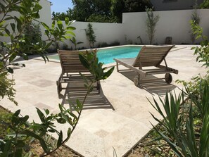 A poolside area with two wooden lounge chairs and a small pool. - 10 minutes walk - air-conditioned (Uzès)