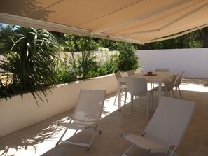 An outdoor patio with a table and chairs, surrounded by potted plants and a white wall. - 10 minutes walk - air-conditioned (Uzès)