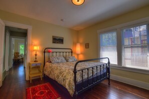 A bedroom with a bed, two bedside lamps, a red rug, and a window with blinds. - Viking House - Walk to campus! (Missoula)