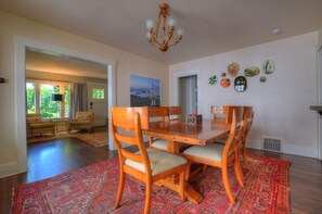 A dining area with a wooden table and chairs, a chandelier, and a red patterned rug. - Viking House - Walk to campus! (Missoula)
