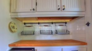 Una cocina con armarios blancos, encimera de madera y horno empotrado.