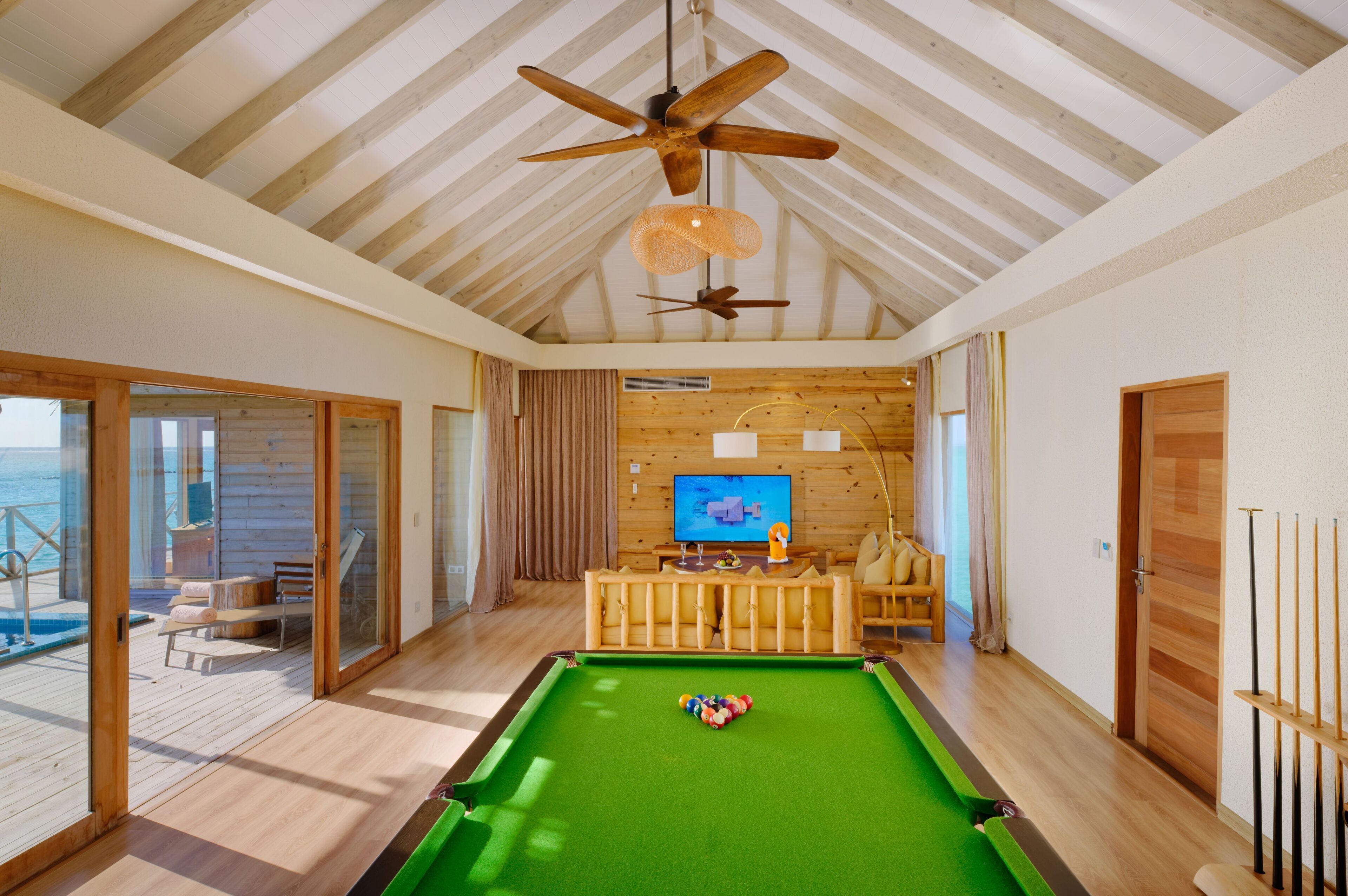 A pool table in a room with wooden floors and a ceiling fan.