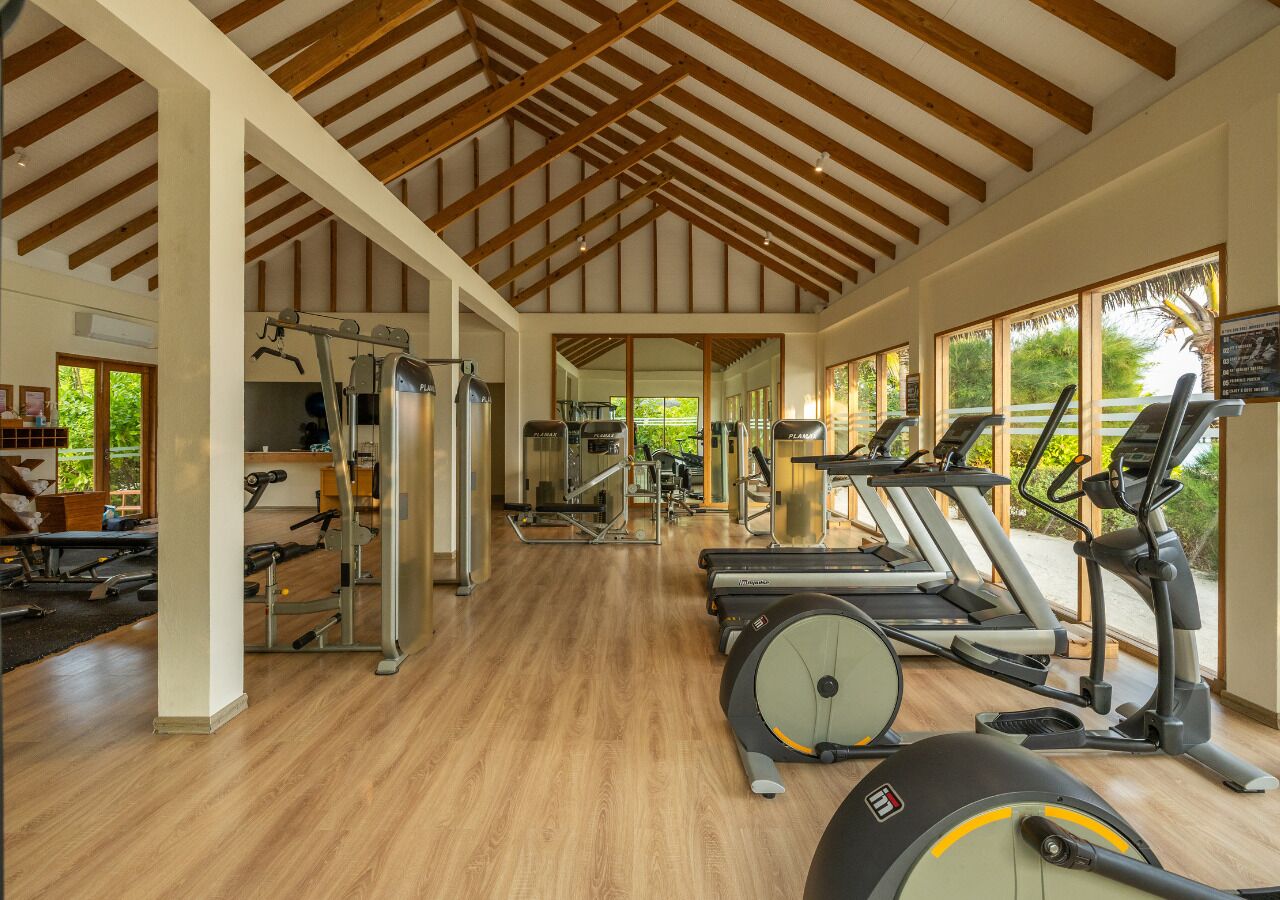 Un gimnasio con cintas de correr, elípticas y equipo de pesas.