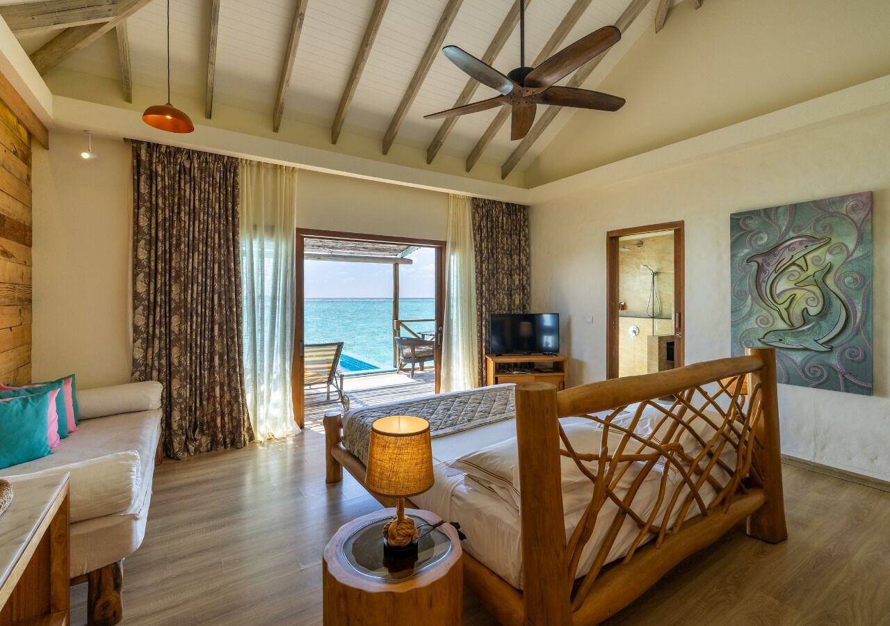 Habitación de hotel con cama, escritorio, silla, televisor y vista al mar.