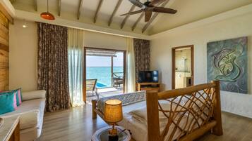 Habitación de hotel con cama, escritorio, silla, televisor y vista al mar.
