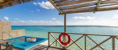 A wooden deck with a pool, a lifebuoy, and a clear view of the ocean.