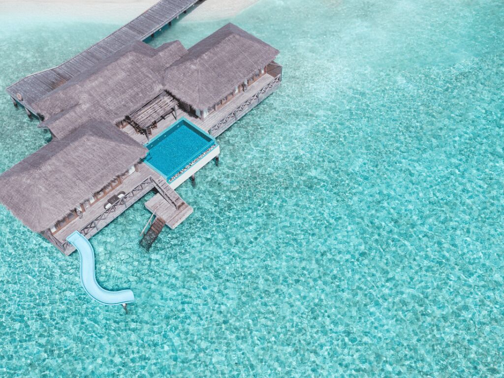 An overwater bungalows with a swimming pool and a thatched roof.