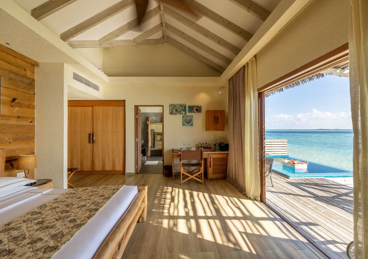 Une chambre à coucher avec un lit, un bureau en bois et une vue sur l’océan.