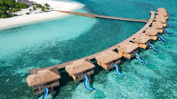 An overwater bungalows with thatched roofs and blue slides, connected by a wooden walkway over clear turquoise water. - You & Me Maldives - Adults Only - Premium All-Inclusive (Uthurumaafaru)
