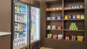 A refrigerated beverage cooler with various drinks and a snack shelf stocked with different packaged foods.