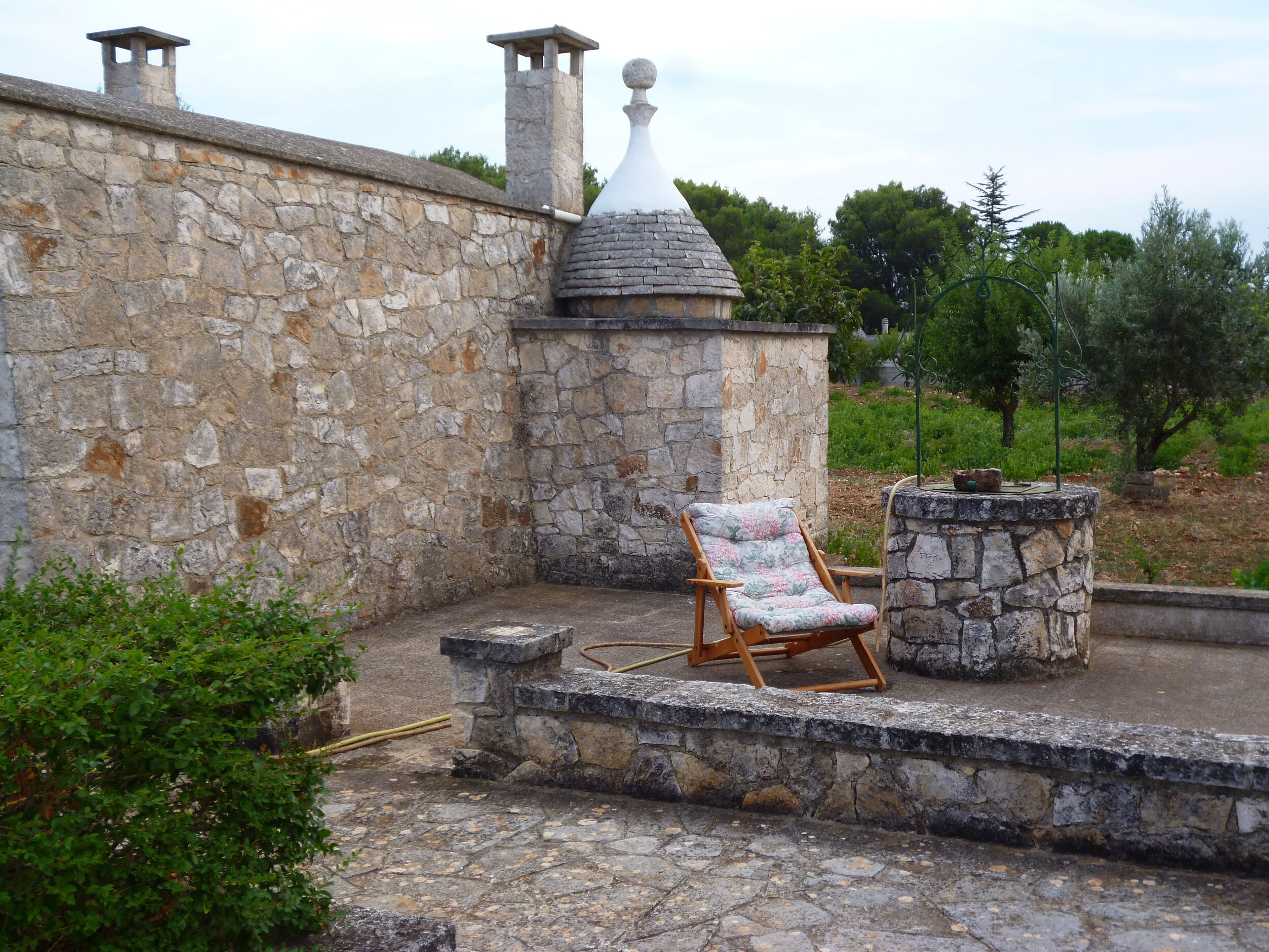 Un patio de piedra con una silla de madera y una mesa de piedra.