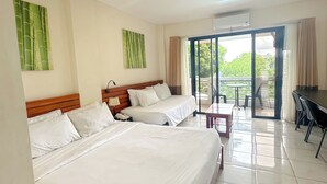 Habitación de hotel con dos camas, un balcón y zona de comedor.