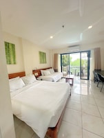 Habitación de hotel con dos camas, un balcón y zona de comedor.