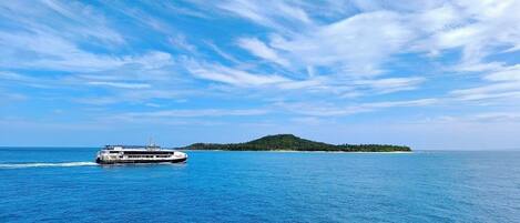 A ferry traveling on a calm sea with a small island in the distance.