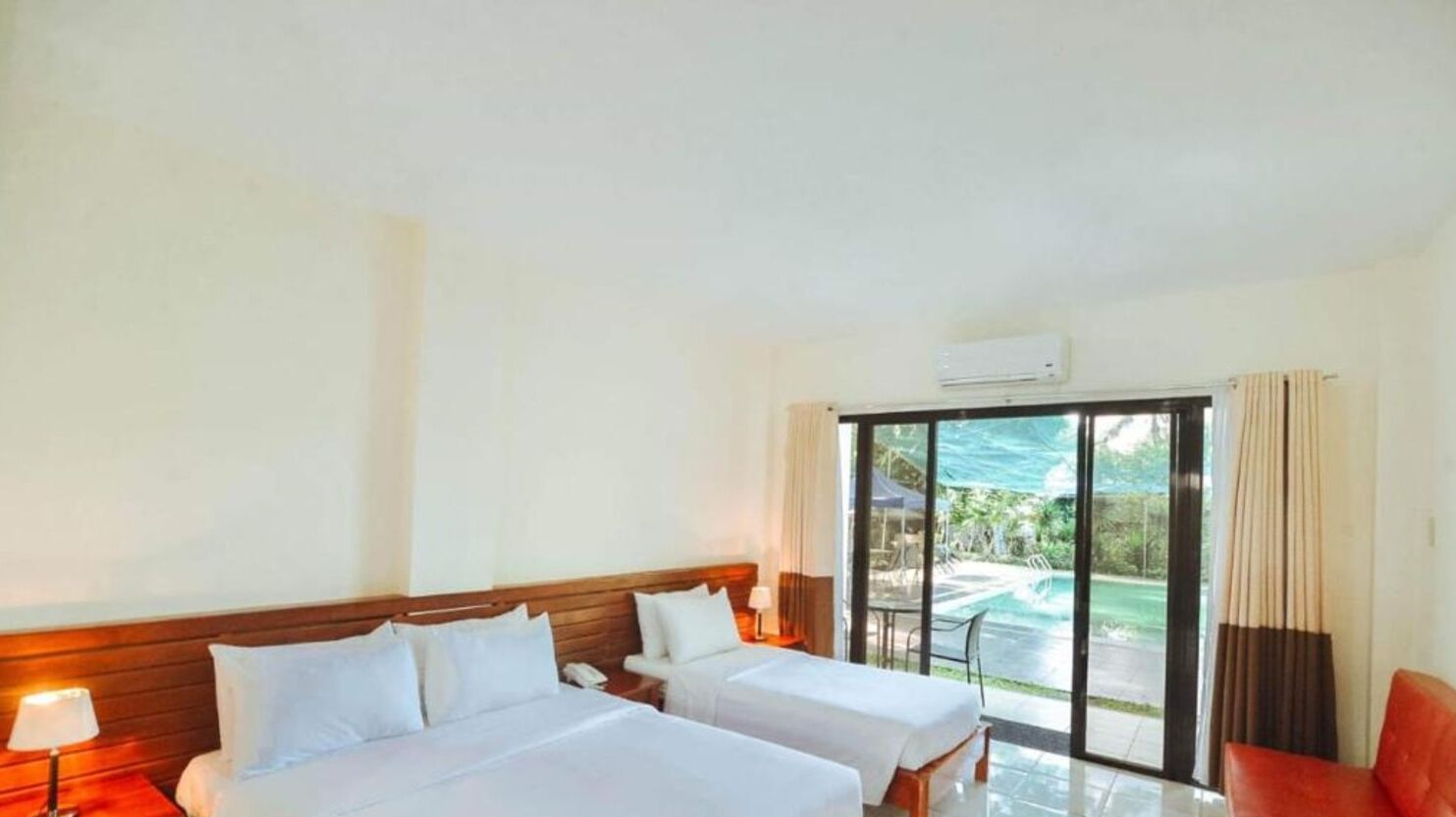 A hotel room with two beds, a large sliding glass door leading to a pool area, and an air conditioning unit on the wall.