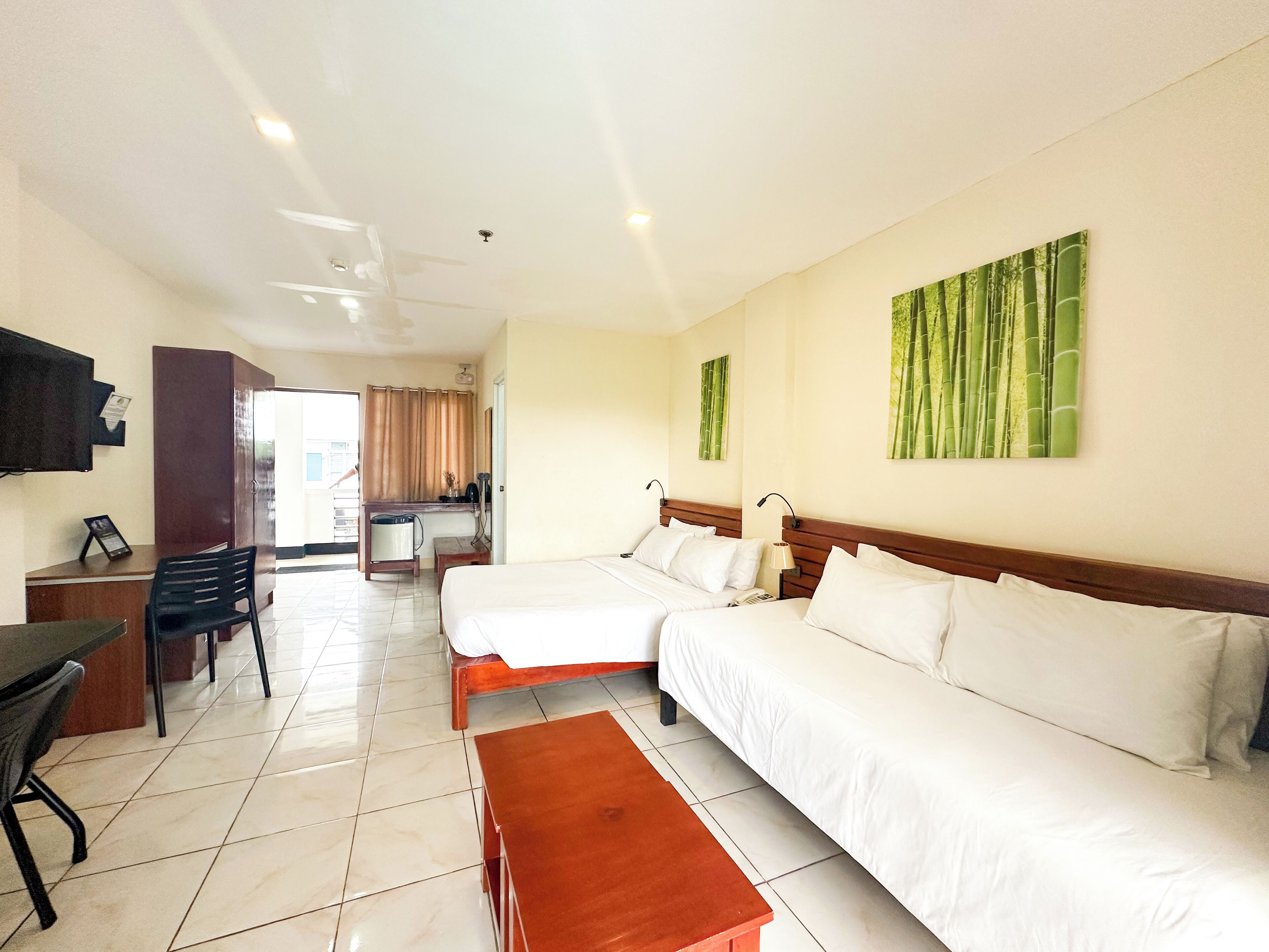 A hotel room with two beds, a desk, a chair, and a small table.
