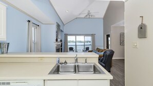A kitchen with a large window, a ceiling fan, and a view of the outdoors.