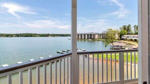 A lakeside view from a balcony with a clear sky, dock, and residential buildings in the background.