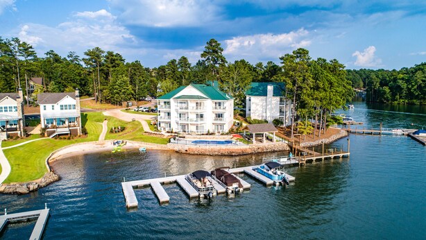 A lakeside property with a dock, boats, and a large building with multiple balconies.