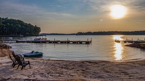 A beach with a boat, chairs, and a pier extending into calm water.