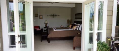 An open door to a bedroom with a bed, a chair, a nightstand, and a lamp.