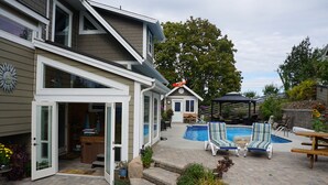 Ein Garten mit Swimmingpool, Liegestühlen und einer überdachten Terrasse.