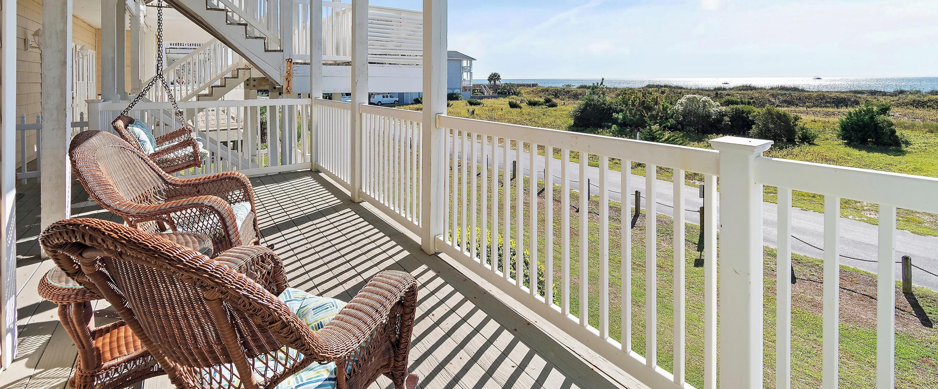 A balcony with wicker chairs and a view of the sea.
