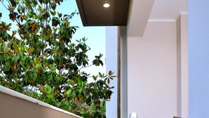 An outdoor patio with a table and chairs, surrounded by a low wall and a tree. - Mastiha Villas in Town (Chios)