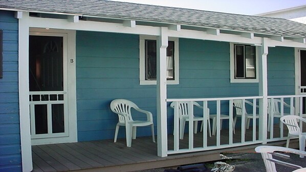 A blue house with a porch, white railings, and two white plastic chairs. - Cute and Cozy.  Short walk to Sand.  Close to Attractions. (Hampton)