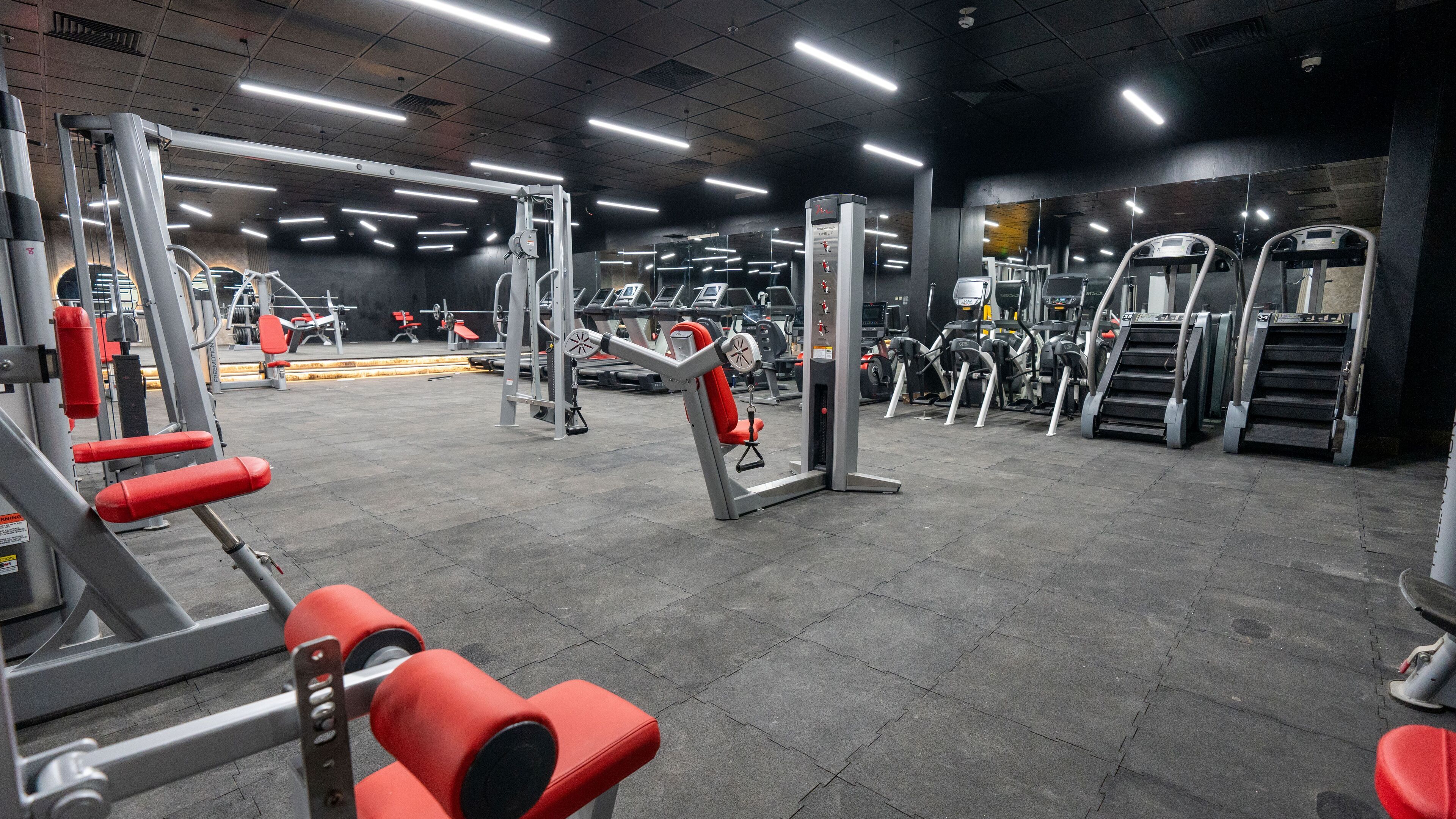 A gym with various exercise equipment, including treadmills, weight machines, and free weights.