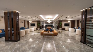 A spacious lobby with a central seating area, multiple sofas, and a large TV screen. - Brzeen Hotel - Riyadh - فندق برزين الرياض (Riyadh)