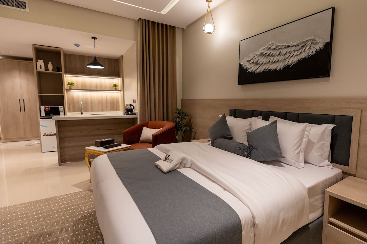 Una habitación de hotel moderna con una cama grande, un escritorio y una kitchenette.