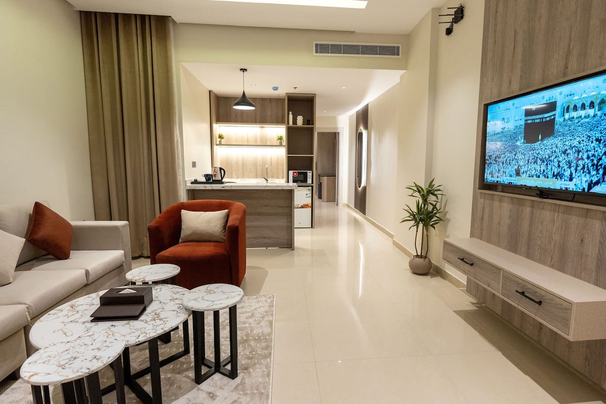 Una sala de estar moderna con un sofá, sillones, una mesita de centro y un televisor montado en la pared.