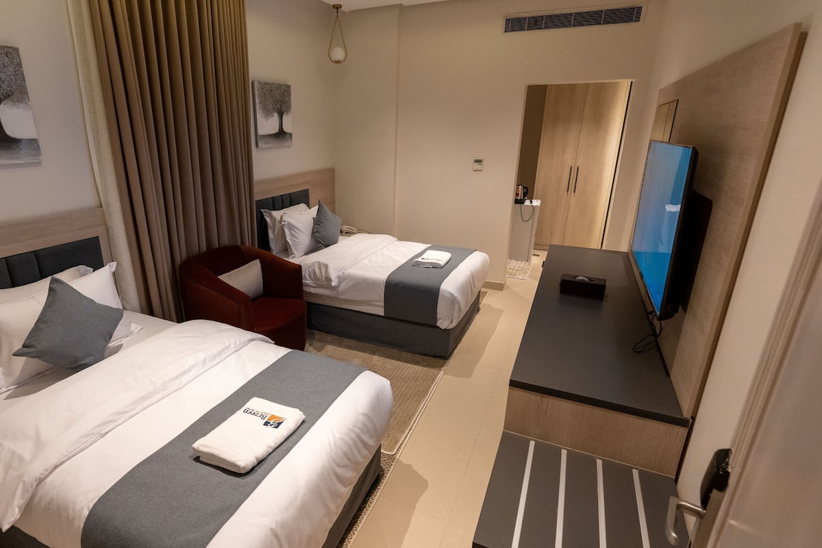 Habitación de hotel con dos camas, un escritorio, televisión y armario.