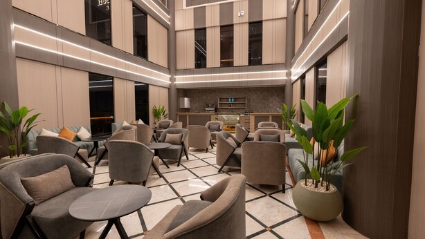 A modern lobby with a central bar area, seating arrangements, and decorative plants. - Brzeen Hotel - Riyadh - فندق برزين الرياض (Riyadh)