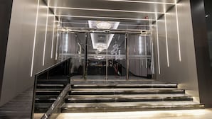 A modern hotel lobby with a grand staircase, a reception desk, and a chandelier. - Brzeen Hotel - Riyadh - فندق برزين الرياض (Riyadh)