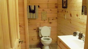 Een betegelde badkamer met toilet, wastafel en een bordje met de vermelding 'warm bad'.