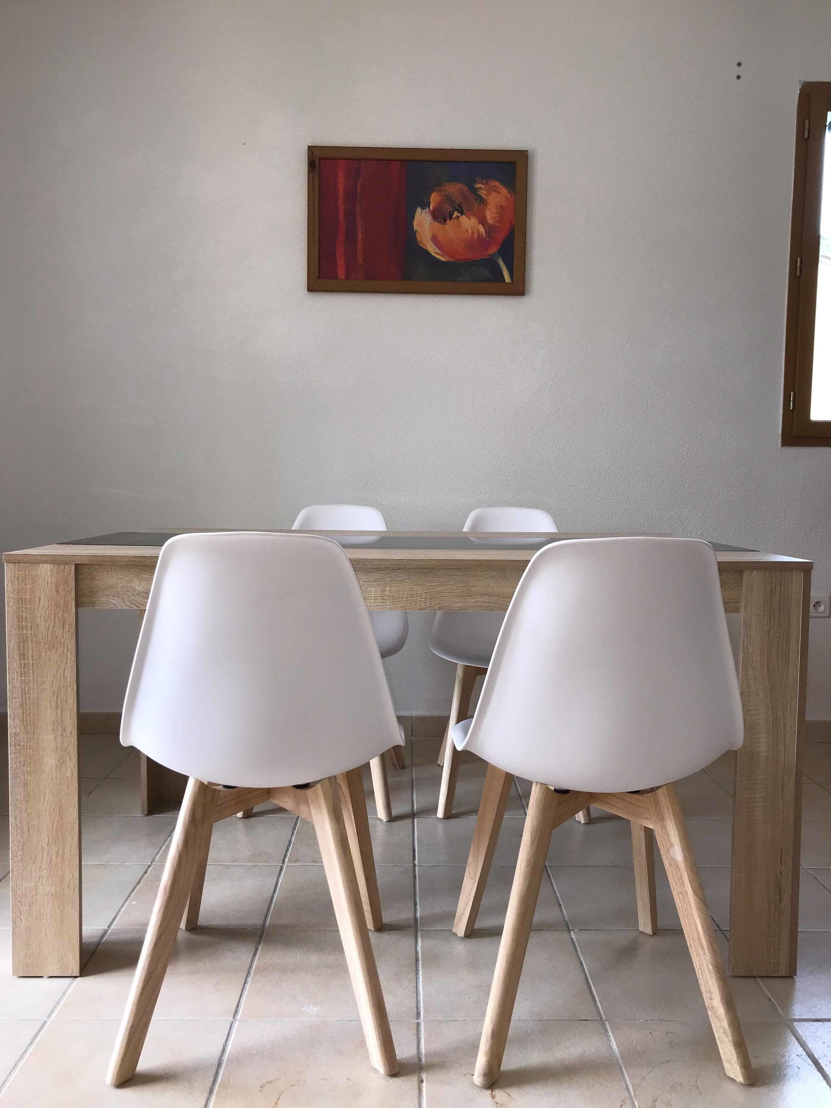 A dining area with a wooden table and white chairs.