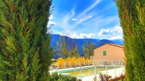 A pool area with a view of mountains and a building in the background. - Résidences La Tour du Guet (Montbrun-les-Bains)