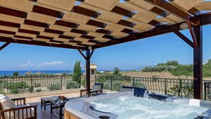 Ein Whirlpool mit Meerblick, Gartenmöbel und eine Pergola.
