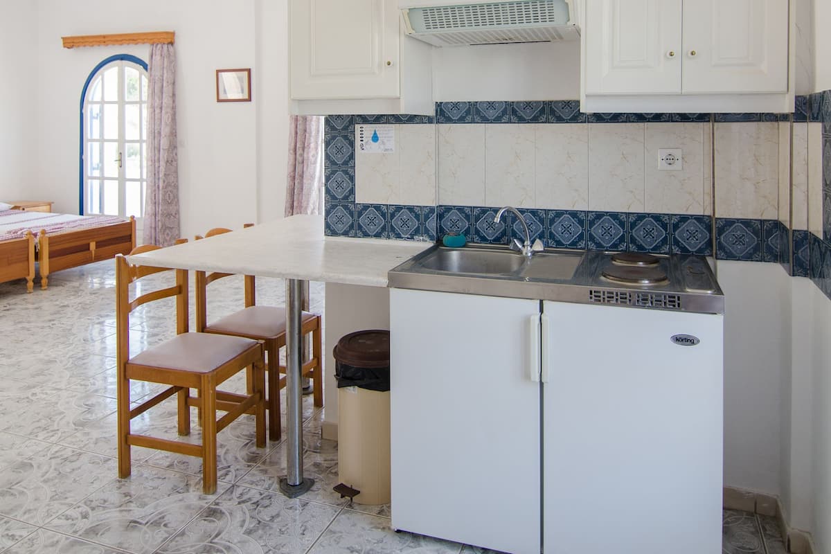 A compact kitchen with white cabinets, a small refrigerator, and a dining area with a table and chairs.