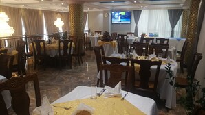 A restaurant with multiple tables set for dining, a chandelier, and a television screen on the wall. - Lan Tian International Hotel (Addis Ababa)