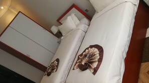 A hotel room with a bed, white linens, and a decorative pillow. - Lan Tian International Hotel (Addis Ababa)