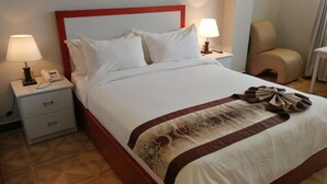 A hotel room with a neatly made bed, two bedside lamps, a telephone, and a chair. - Lan Tian International Hotel (Addis Ababa)