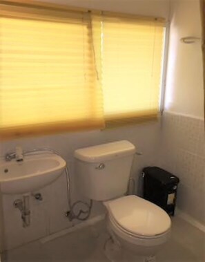 A small bathroom with a toilet, sink, and window blinds.