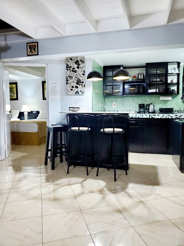 A modern kitchen with a central island, black bar stools, and a dining area with a table and chairs.