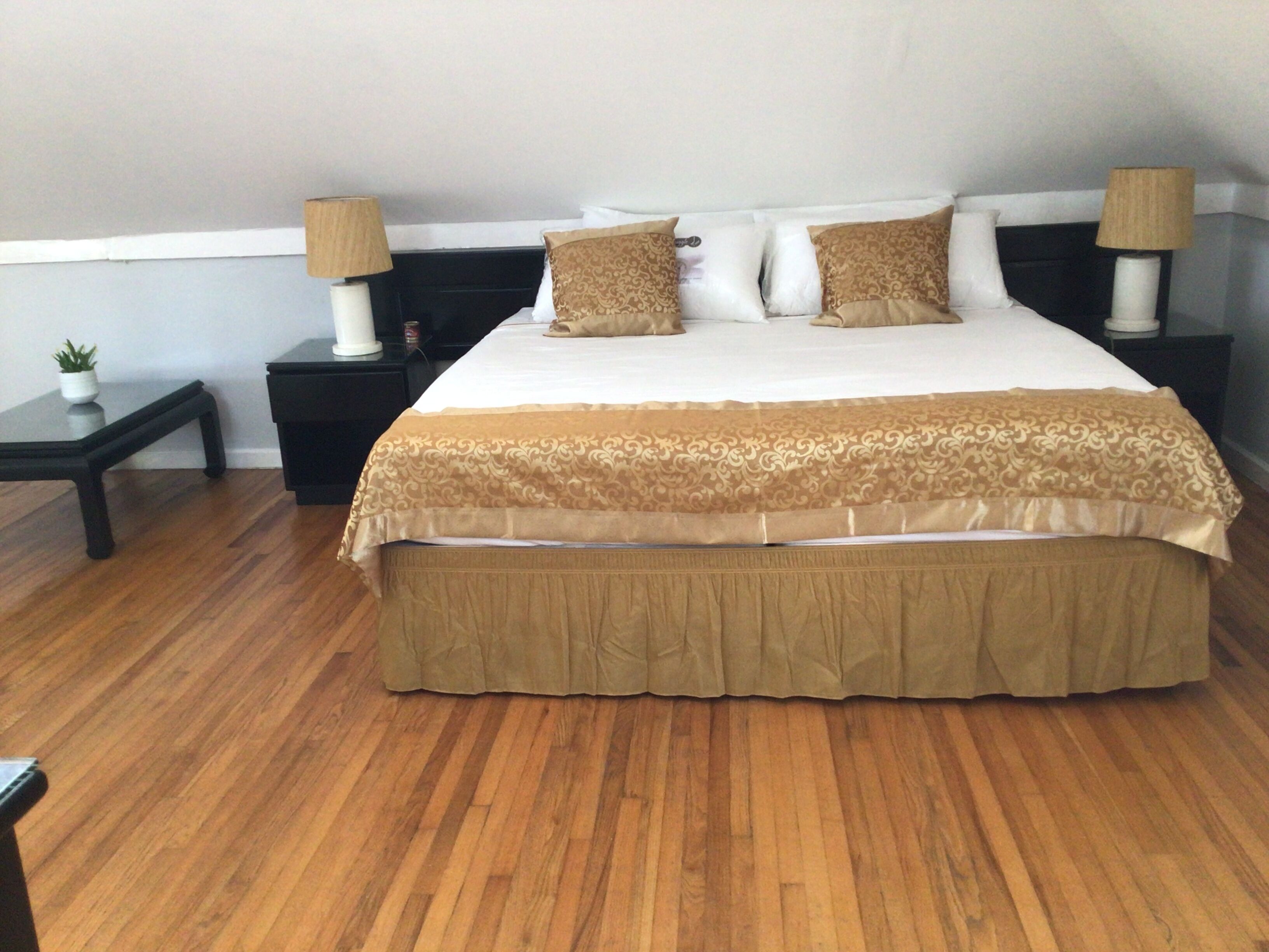A neatly arranged bedroom with a large bed, two bedside tables, and a small table with a plant.
