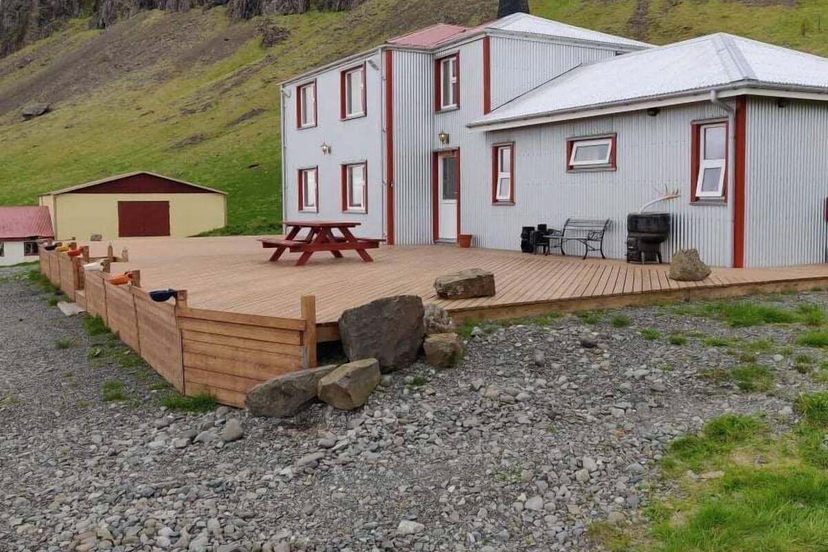 Un chalet rustique doté d’une terrasse en bois, d’une table de pique-nique et d’un espace barbecue.