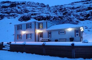 Un edificio de dos pisos con techo nevado y una terraza de madera en la parte delantera.